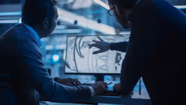 Die cast engineers designing with a blueprint on a screen